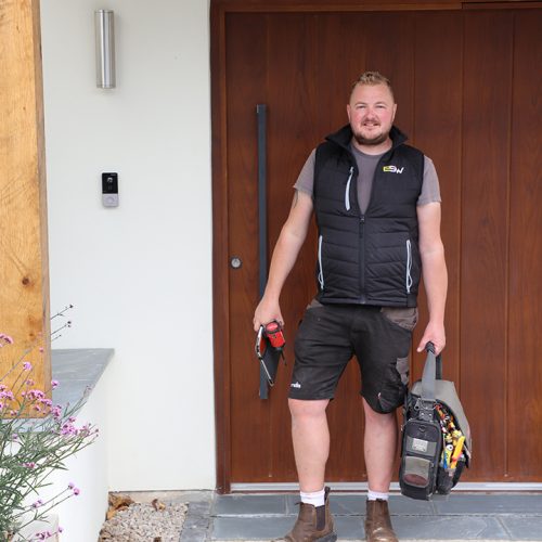 Electrician standing outside front door with toolbag